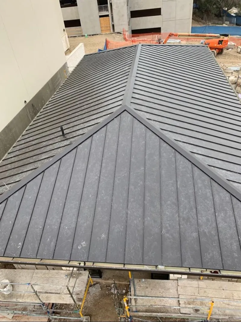 Commercial metal roof construction with crane equipment in Colonie